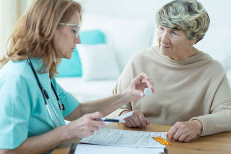Mature physician prescribing medicament for elder woman