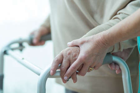 Close-up of woman using walker assisted by carerの写真素材