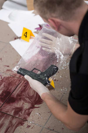 Police officer is looking at secured pistolの写真素材