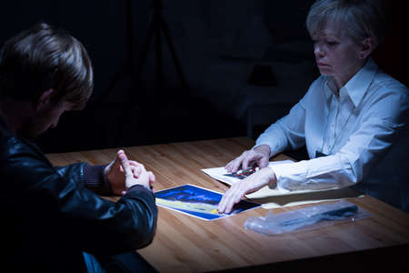 Female detective is showing to the man a photographyの写真素材