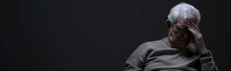 Panoramic photo with dark background showing depressed elder manの写真素材
