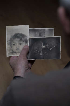 Grandfather holding old pictures of his family membersの写真素材