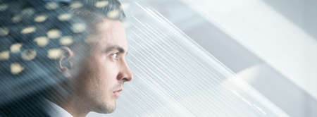 Young man is looking through the windowの写真素材