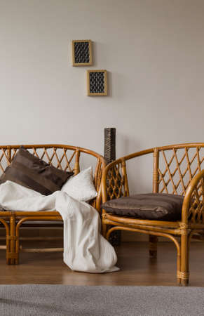 Two stylish brown wicker chairs in a modern houseの写真素材