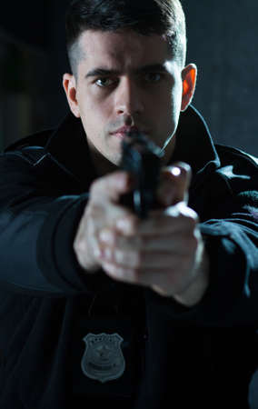 Young strong policeman ready for shoot to criminalの写真素材