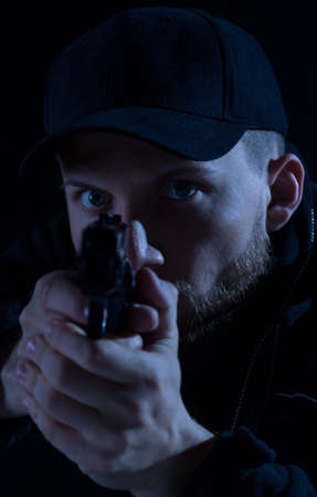 Young brave policeman prepared for shooting to criminalの写真素材
