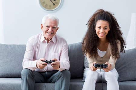 Grandpa and granddaughter holding joysticks and playing games