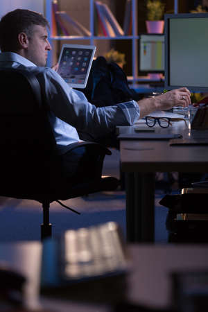 Young man is working long hours in the officeの写真素材