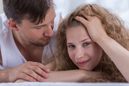 Happy young couple lying in bed togetherの写真素材