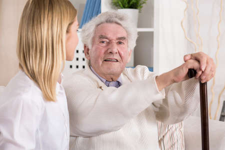 Image of carer and old male with walking stick
