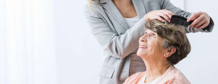 Female caregiver making senior woman new hairstyle