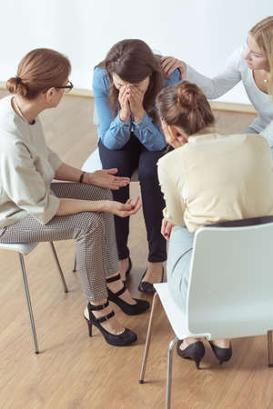 Depressed young woman crying on psychotherapy meetingの写真素材