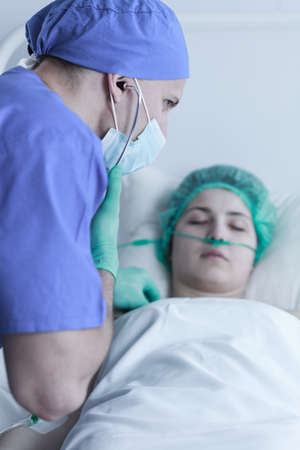 Picture of a medic examining person after operation with stethoscope