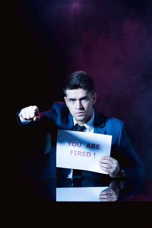 Image of boss holding card with writing you are fired