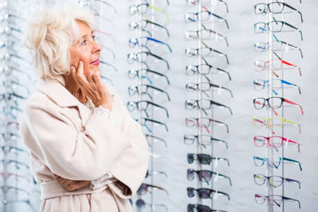 Picture of pensive senior lady chosing eyeglass frames