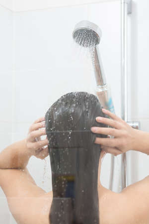 Brunette girl washing her hair under shower