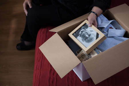 Photo of widow packing things of husband into boxの写真素材