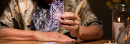 Old fortune teller is looking at tarot