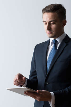Stylish businessman standing with tablet on white backgroundの写真素材