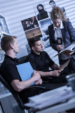 Young policewoman and policemen during criminal investigationの写真素材