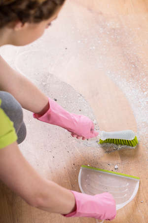 Young woman sweeping the floor with small brush and dustpanの写真素材