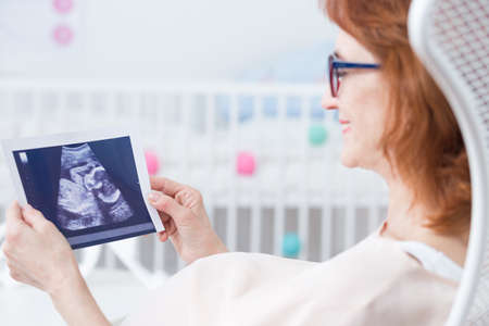 Pregnant middle aged woman looking at usg photo