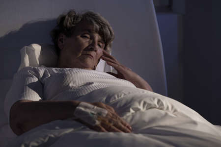 Sad elderly lady alone in hospital during night