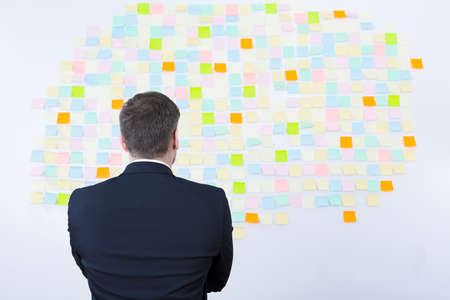 Man in suit standing back view in front of sticky notes wall