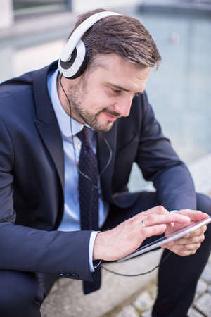 Photo of entrepreneur with headphones listening music on tablet