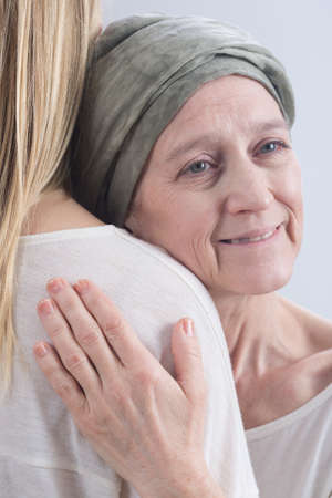 Positive cancer woman with headscarf embracing young girl