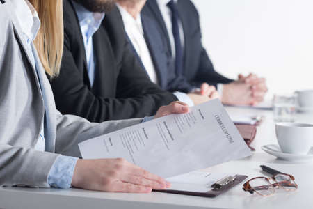 Woman holding CV sittting next to three businesspeople beside table