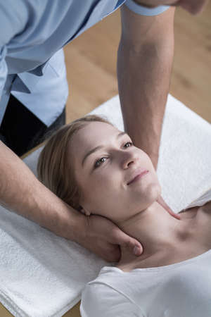 Physiotherapist stabilizing young woman's neck with his hands