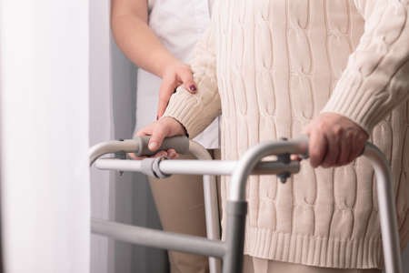 Close-up of older woman walking with walkerの写真素材