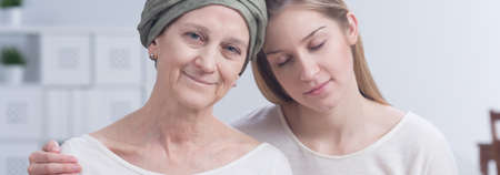 Cancer woman with positive attitude embraced by young, blonde girl, panorama.の写真素材