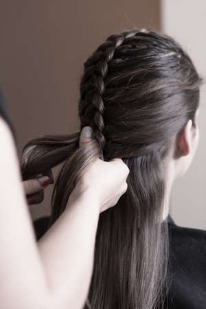 Hairdresser making a dutch braid - close up of hands