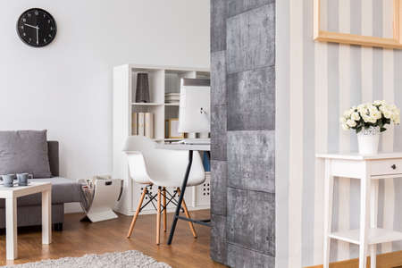 Office room and living room combined. Light interior with decorative wallpaper.