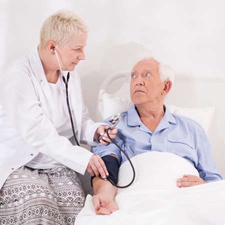 Medical examination of senior man lying in bed