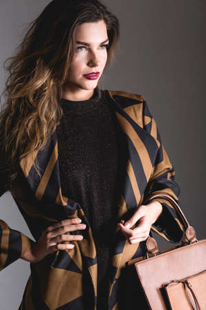 Elegance woman in brown outfit, standing on grey background