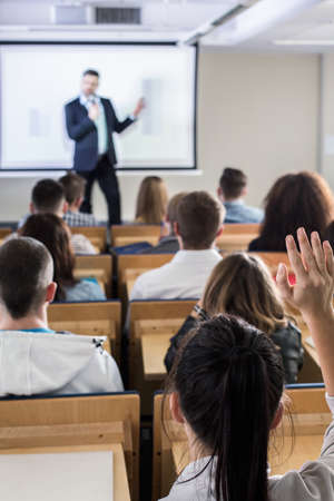 Woman back view raising hand during conference in lecture hallの写真素材