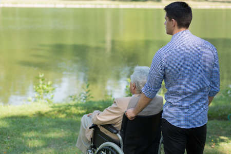 Disabled senior man sitting at the lakeの写真素材