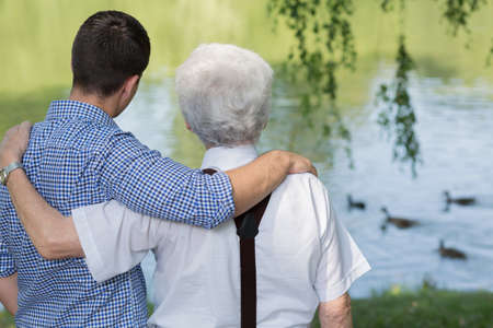 Grandfather with mature grandson at the lakeの写真素材