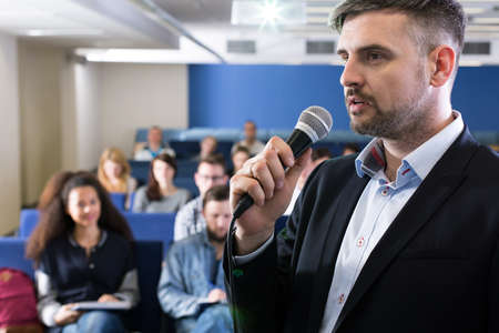 University teacher with microphone giving lecture for students