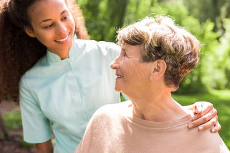 Young nurse is hugging elder lady in the gardenの写真素材