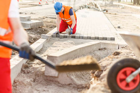 Photo of young construction worker laying new cobblestonesの写真素材
