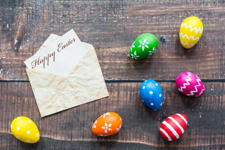 Shot of colorful Easter eggs on a table and an envelope with greetingsの写真素材