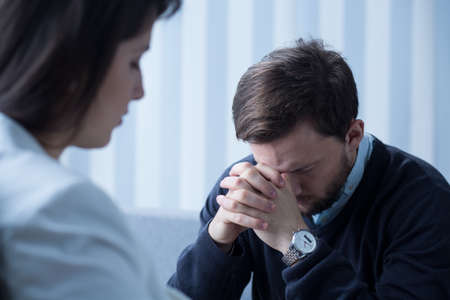 Young worried man on psychotherapy with doctor