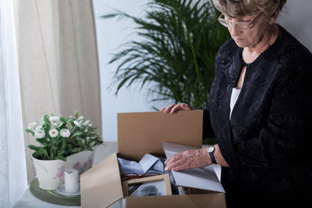 Widow is closing box with things of her husbandの写真素材