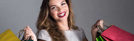 Young beautiful girl in make up addicted to shopping. Holding bags with new clothesの写真素材