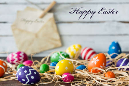 Decoration with color easter eggs and raffia, light planks and card in the background