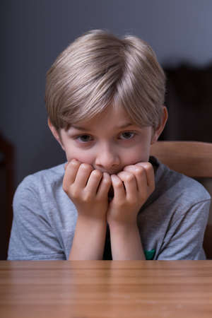 Young scared blonde boy staying home aloneの写真素材